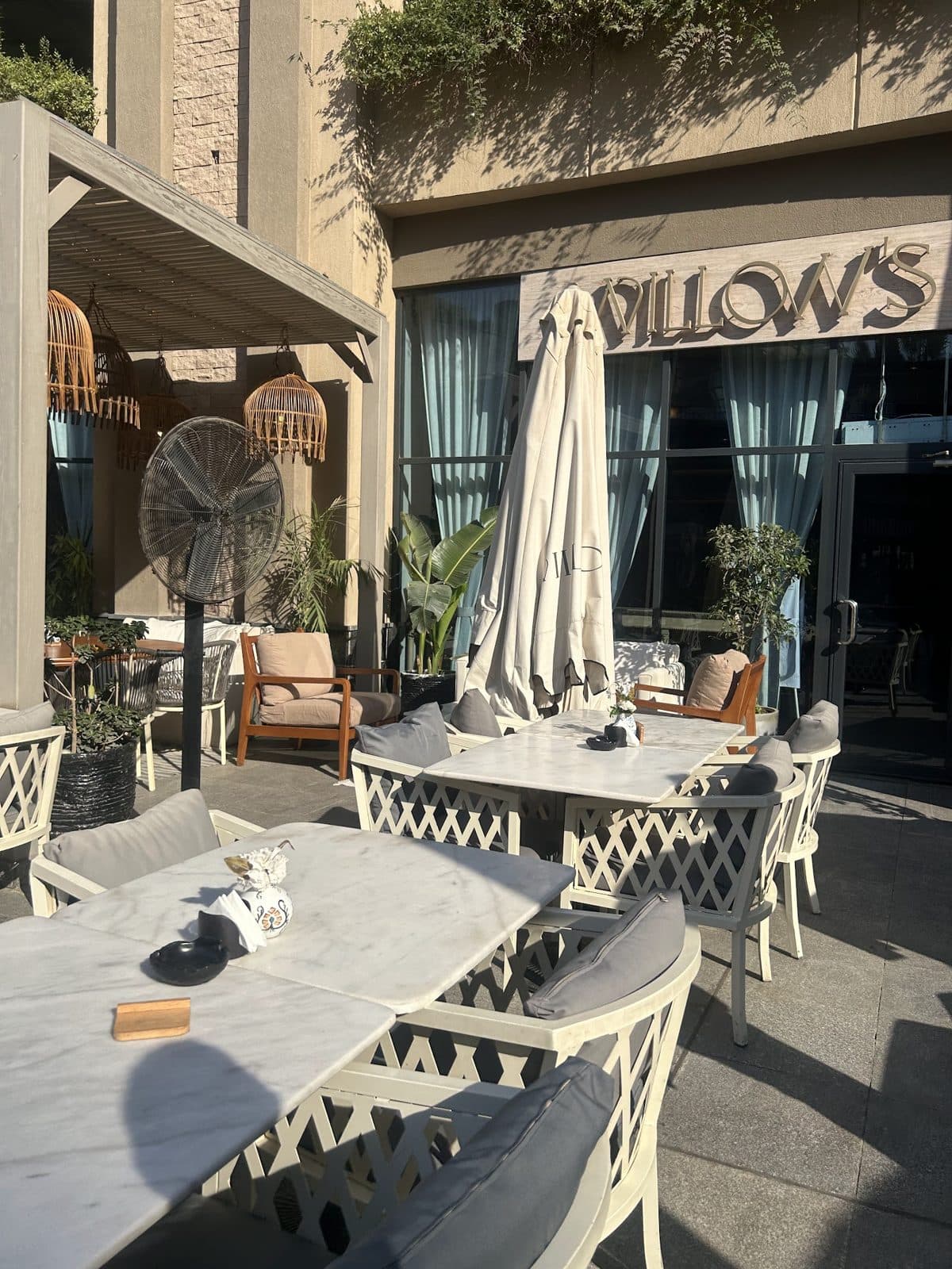 Outdoor terrace seating at Willow's Arkan Plaza, with tables set out beneath the illuminated WILLOW'S signage.